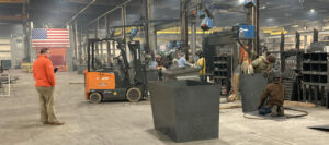 People working in factory with forklift and United States flag in the background