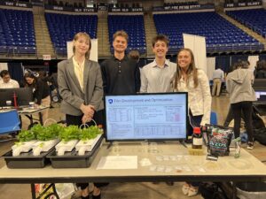 Students stand behind a table with hydroponically grown lettuce plants.